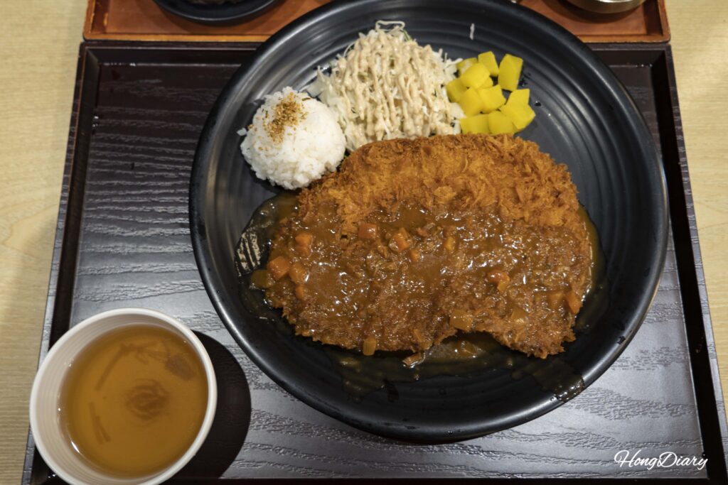 Full plate view of the giant pork cutlet with rice, cabbage, and demi-glace sauce at Plating Gimhae Airport