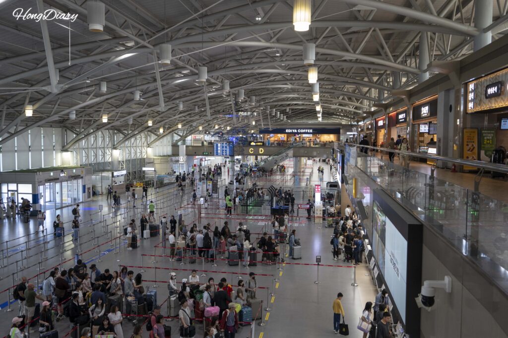 金海国際空港ターミナルの外観と出発する旅行者たち