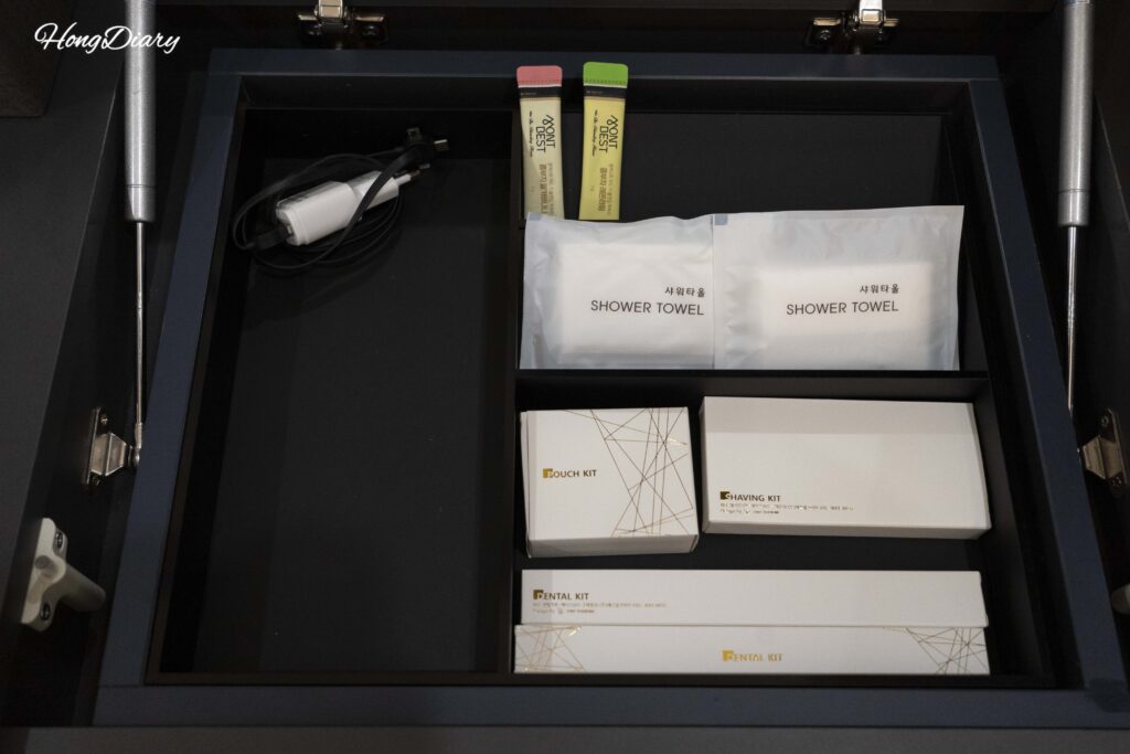 Kit de amenidades gratuitas en el escritorio del Giverny Hotel en Gyeongju incluyendo cepillo dental, rasuradora y té de kombucha