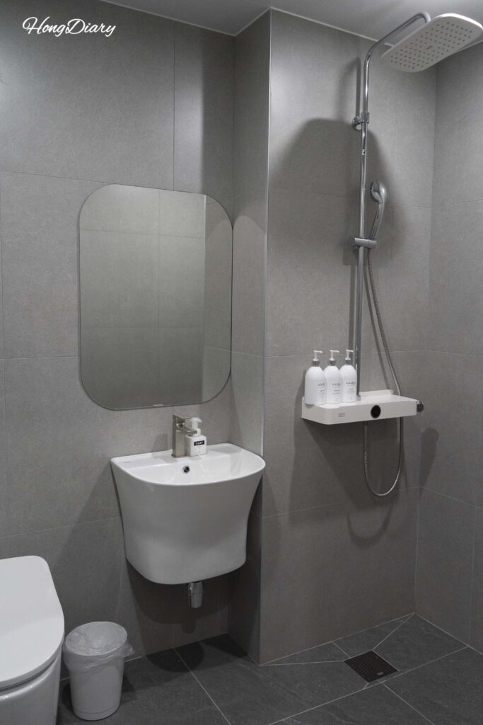 Baño limpio y moderno con ducha, inodoro con bidé y productos de aseo en el Giverny Hotel en Gyeongju