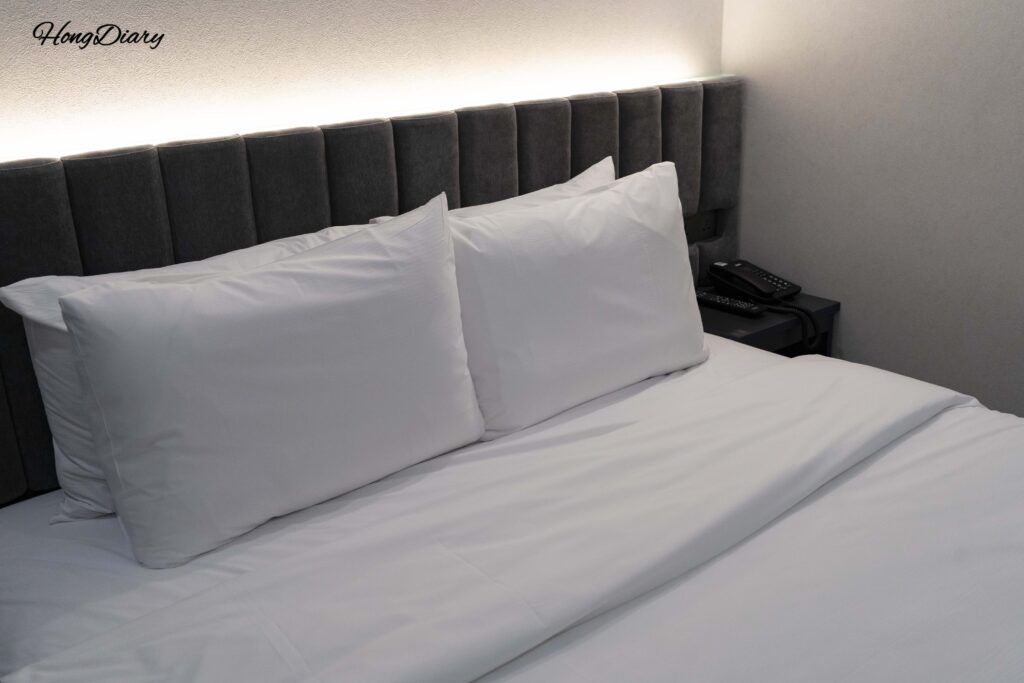 Cama doble con ropa de cama blanca y Smart TV de gran tamaño en la habitación Deluxe del Giverny Hotel en Gyeongju