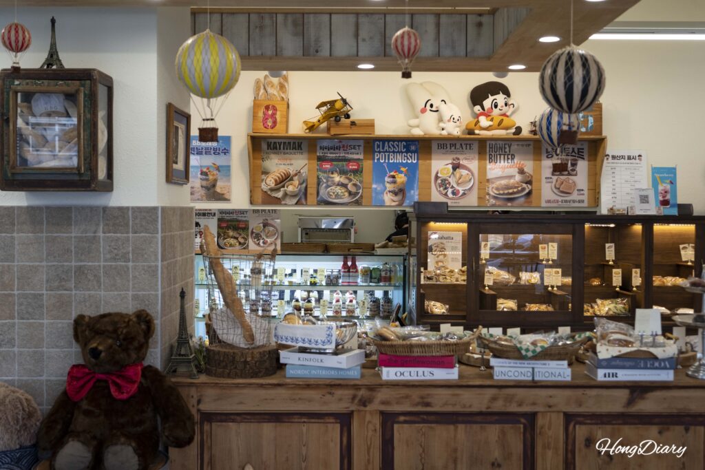 Interior de House of Bread BB mostrando pósters del menú vitrinas de panadería y decoración de la cafetería en Gwangalli