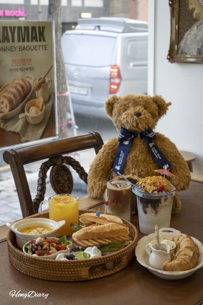 Mesa con pedidos y un peluche de oso en la cafetería House of Bread BB en Gwangalli