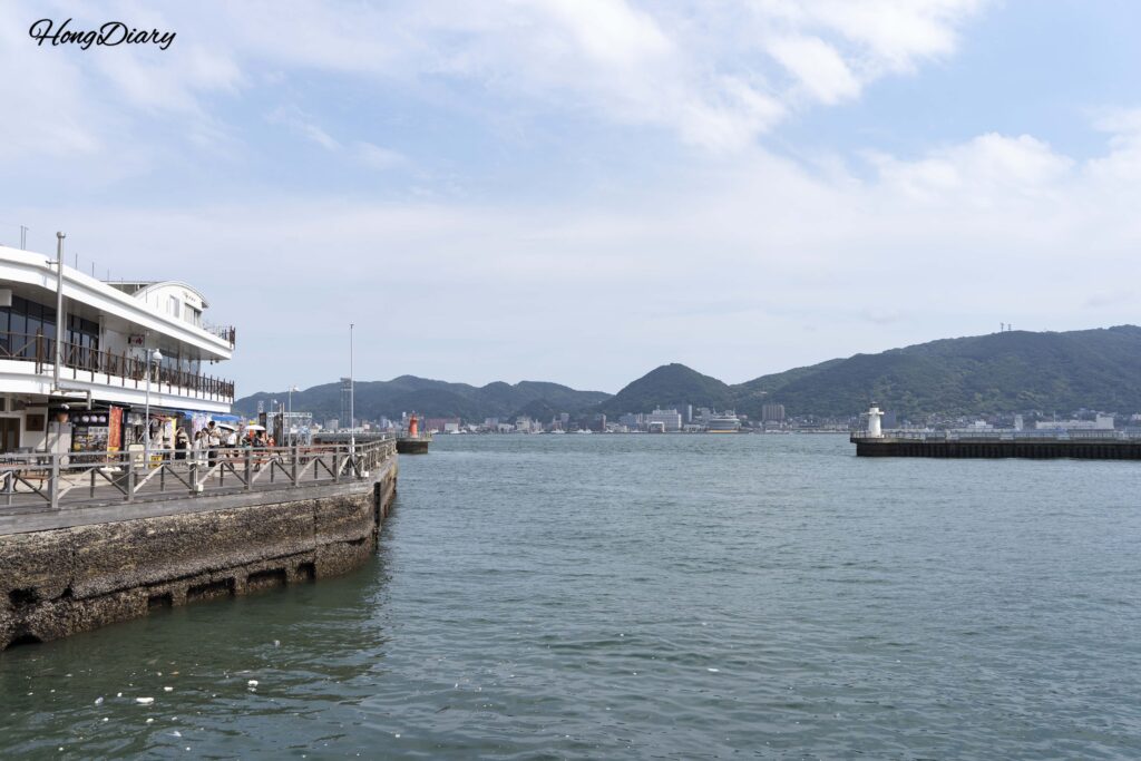 Waterfront boardwalk at Kamon Wharf leading to Karato Market in Shimonoseki, with the ocean visible on the right