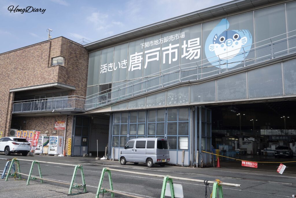 Exterior view of Karato Market building in Shimonoseki under a clear blue sky after the rain stopped