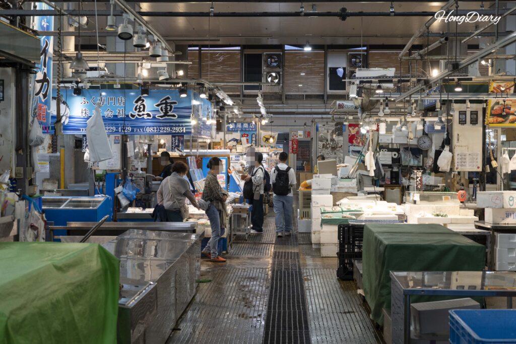 Seafood vendors selling non-sushi items including tempura, croquettes, and grilled skewers inside Karato Market, Shimonoseki