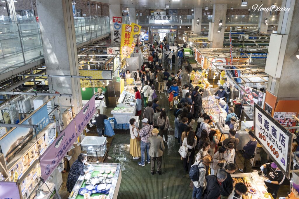 View from the second floor of Karato Market looking down at the crowded first-floor sushi stalls and visitors below