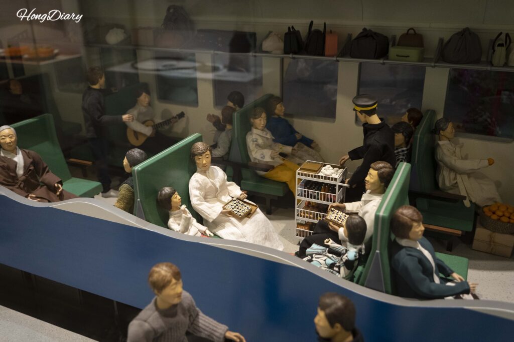 Maqueta detallada de un vagón de pasajeros antiguo con figuras en el Museo Ferroviario de Jinyeong