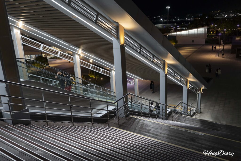 Visitors descending stairs and escalator from the skybridge into North Port Waterfront Park in Busan