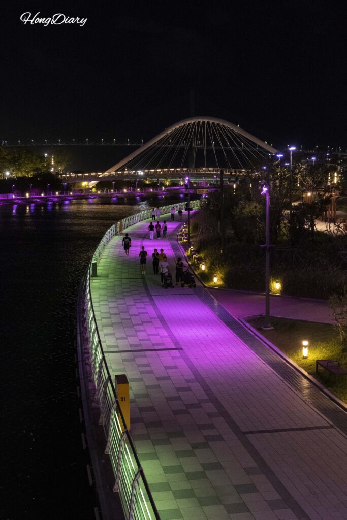 Panorámica nocturna de North Port Waterfront Park en Busan con senderos iluminados a lo largo del paseo marítimo