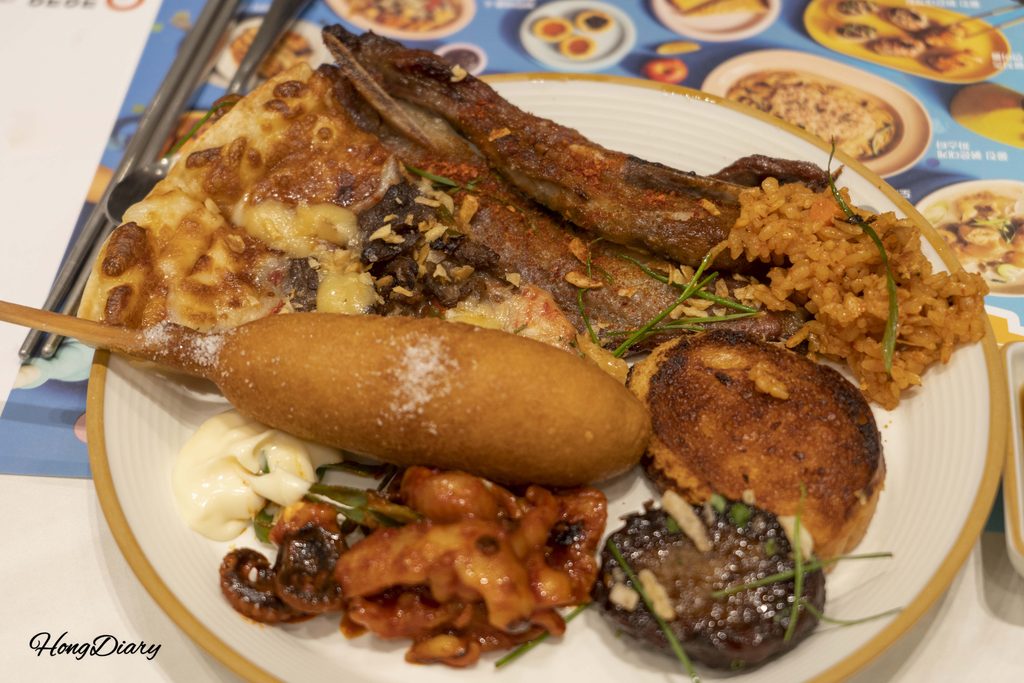 Assorted plate of food from QooQoo buffet including sushi, hot dishes, and sides
