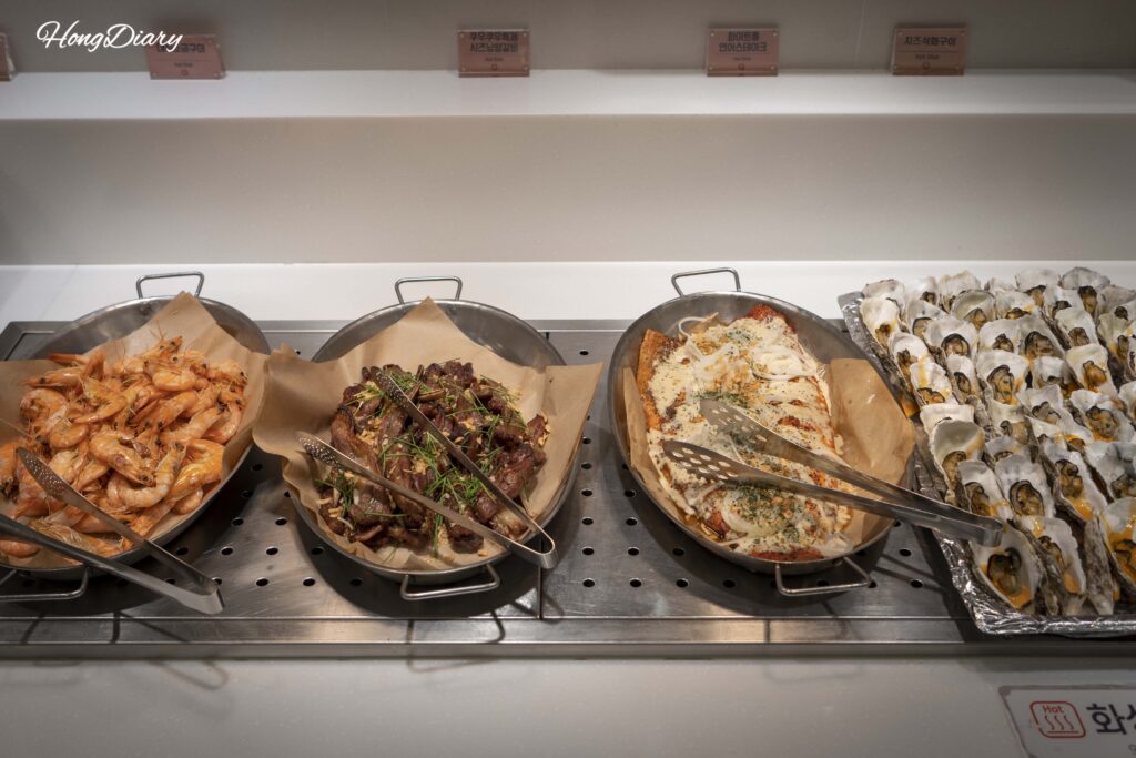 Estación de parrilla en QooQoo con salmón, camarones, ostras y costillas de cordero
