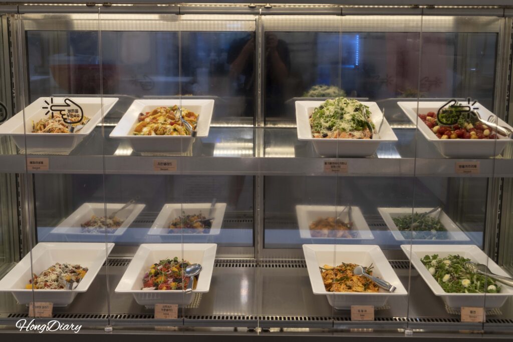 Barra de ensaladas con vegetales frescos y aderezos en el buffet QooQoo