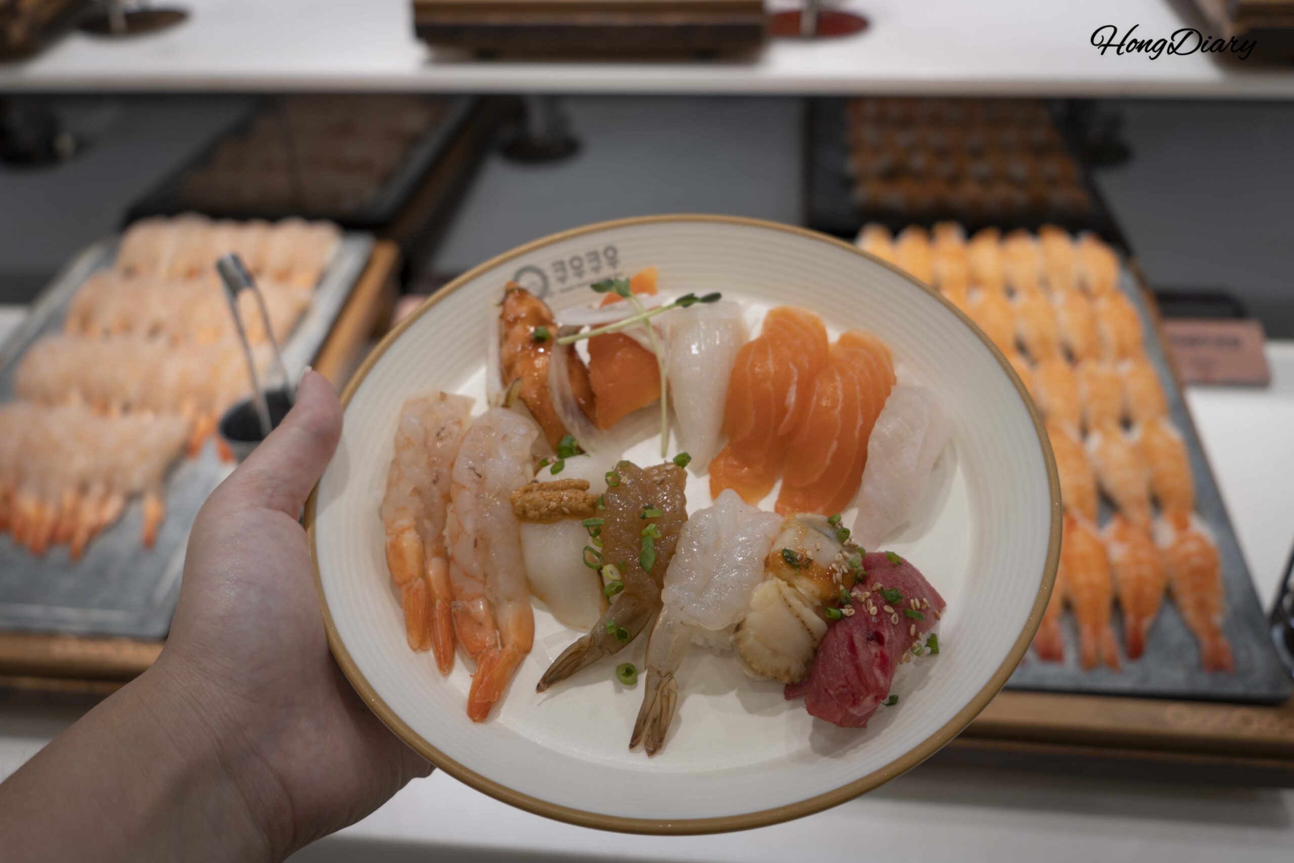 Plato con variedad de sushi seleccionado del mostrador del buffet QooQoo
