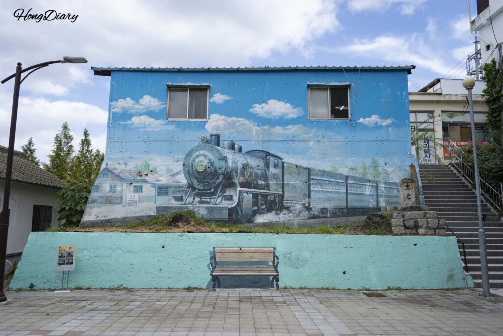 Colorful railway-themed mural painted on a building wall at Jinyeong History Park in Gimhae