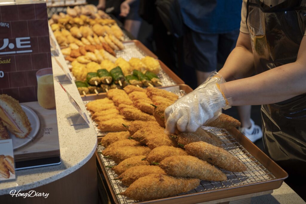 Staff arranging freshly fried whole chili pepper fish cakes at Samjin Fish Cake Yeongdo