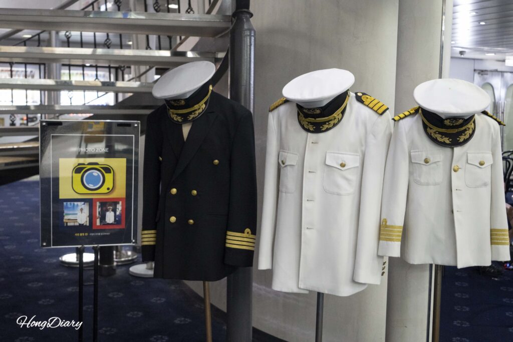 Zona de fotos en el ferry Seonghee donde los pasajeros pueden usar uniformes de capitán en negro y blanco