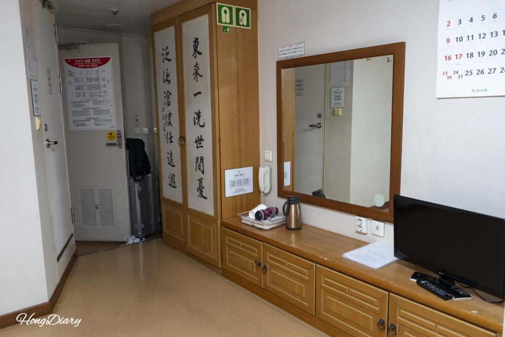 Interior de la habitación coreana del Seonghee mostrando televisor, secador de pelo y almacenamiento