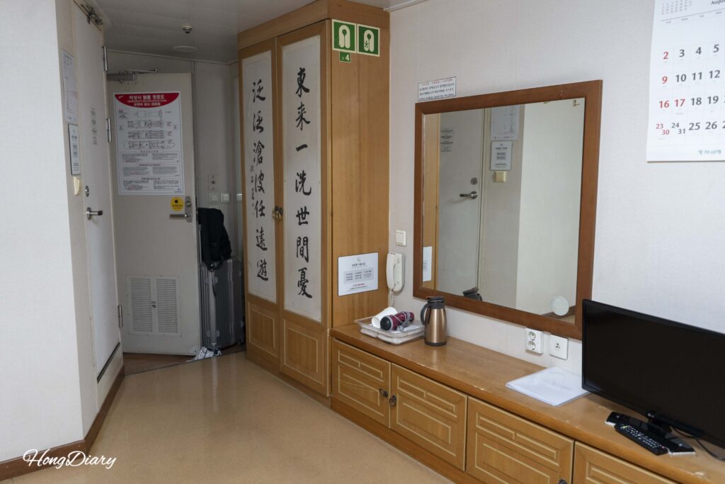 Interior of the Seonghee tatami cabin showing small TV, hair dryer, and storage area