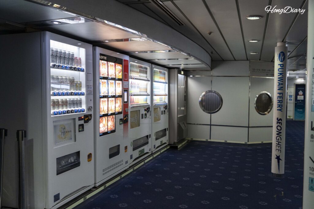 Row of vending machines on Deck 4 of the Seonghee ferry selling beer, ice cream, and drinks