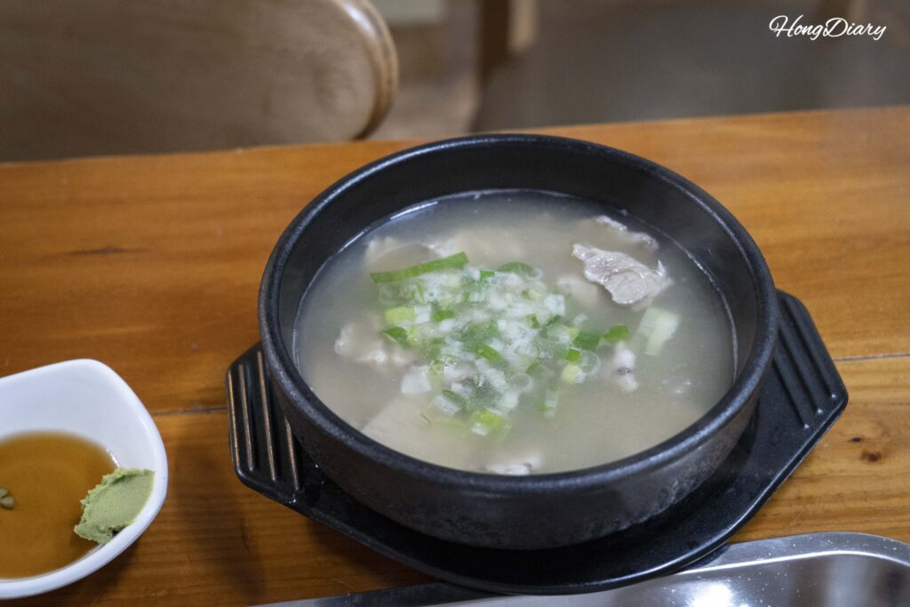 Bowl of dwaeji gukbap (pork bone soup with rice) served bubbling in an earthenware pot at Seonjeongmun in Busan