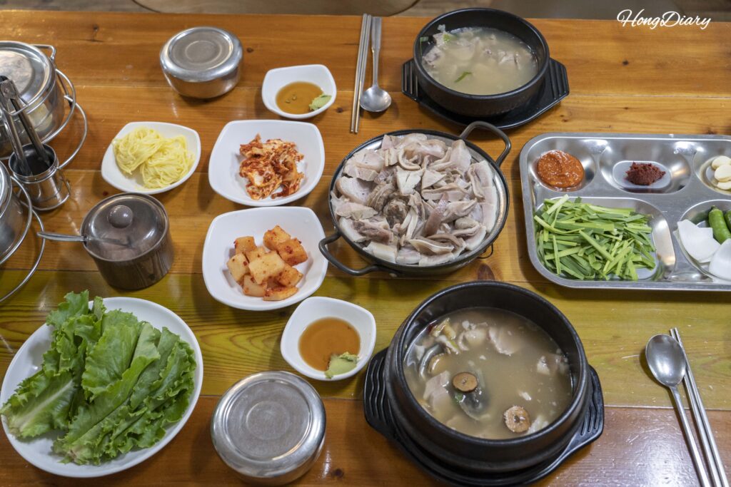 Full table spread at Seonjeongmun Dwaeji Gukbap showing dwaeji gukbap, donsamjeonboktang, and boiled pork platter with side dishes