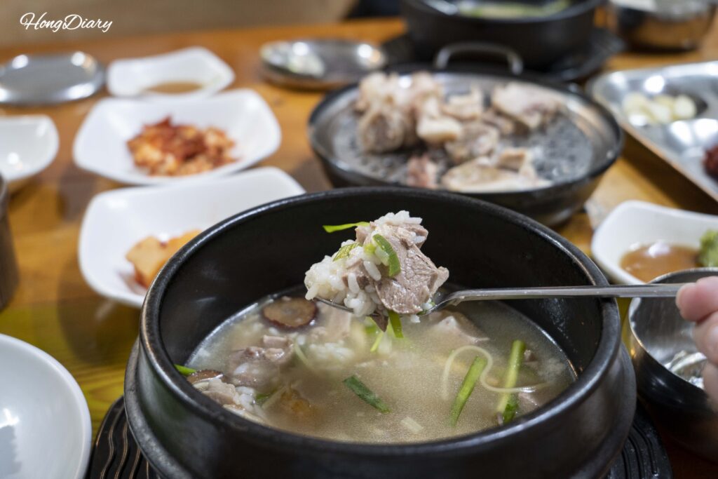 Close-up of a spoonful of milky pork bone broth from the dwaeji gukbap at Seonjeongmun in Danggam-dong, Busan