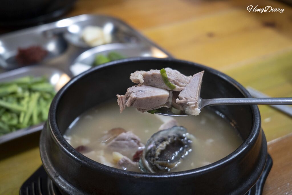 Primer plano de una cucharada del caldo blanco lechoso de sopa de cerdo dwaeji gukbap en Seonjeongmun, Busan
