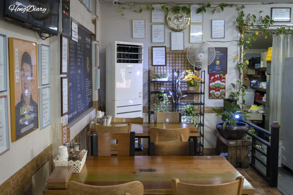 Self-serve side dish counter inside Seonjeongmun Dwaeji Gukbap restaurant in Busan with kimchi and pickled radish
