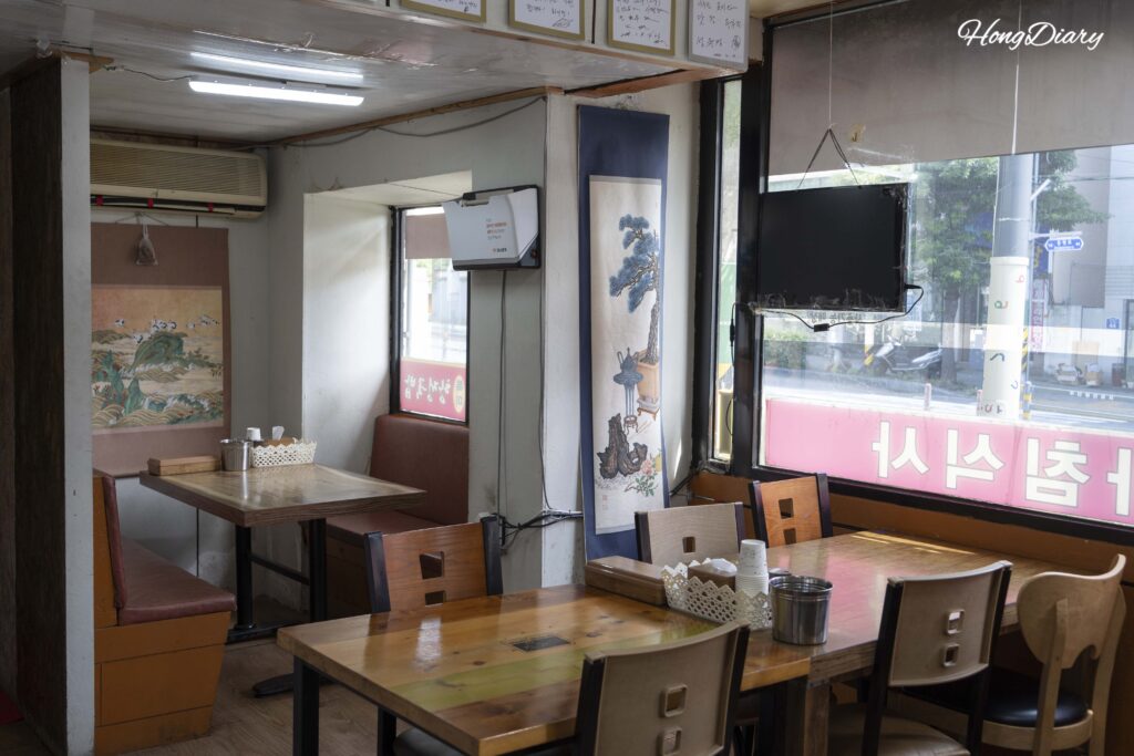 Interior seating area of Seonjeongmun Dwaeji Gukbap with tables and celebrity autographs covering the walls
