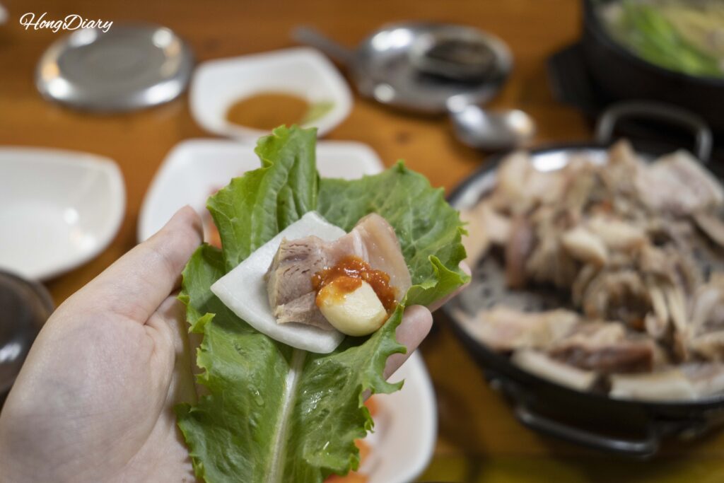 Rebanada de cerdo hervido suyuk envuelta en hoja de perilla con ajo y ssamjang en Seonjeongmun Dwaeji Gukbap, Busan