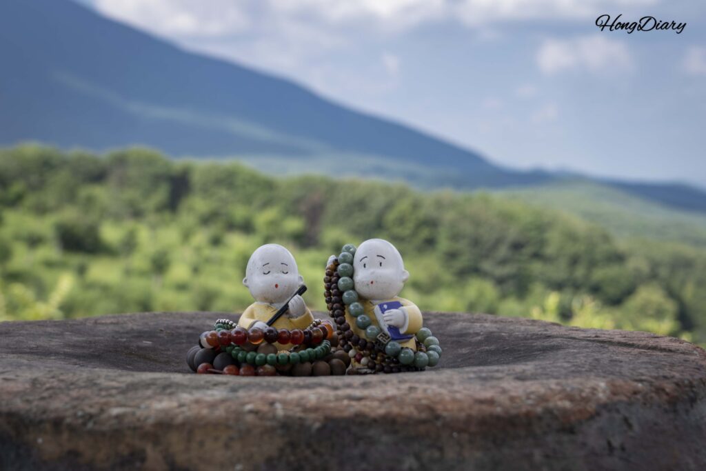 Small ceramic monk figurines displayed alongside prayer beads (yeomju) left by visitors at Seounam Hermitage