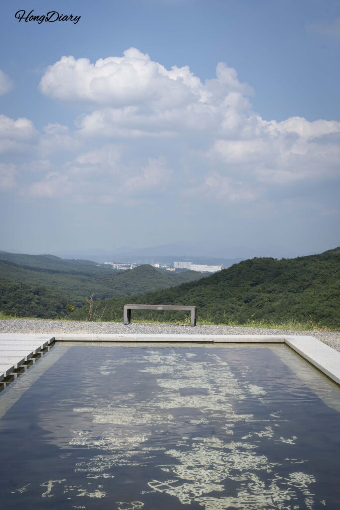 Vertical view of the submerged lacquerwork panels at Seounam Hermitage with blue sky and clouds reflected on the water surface