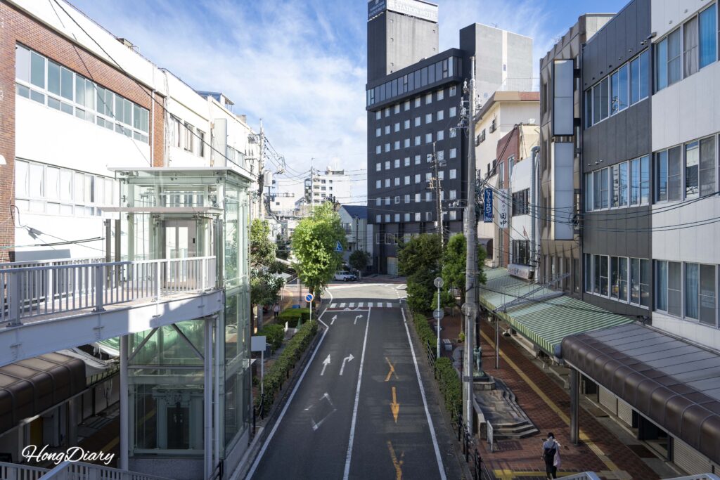 Quiet two-lane road below the Shimonoseki elevated walkway with few pedestrians in the early morning