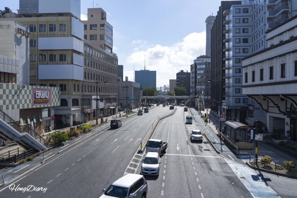 Street-level view from the Shimonoseki elevated walkway with Kaikyo Yume Tower partially visible on the right