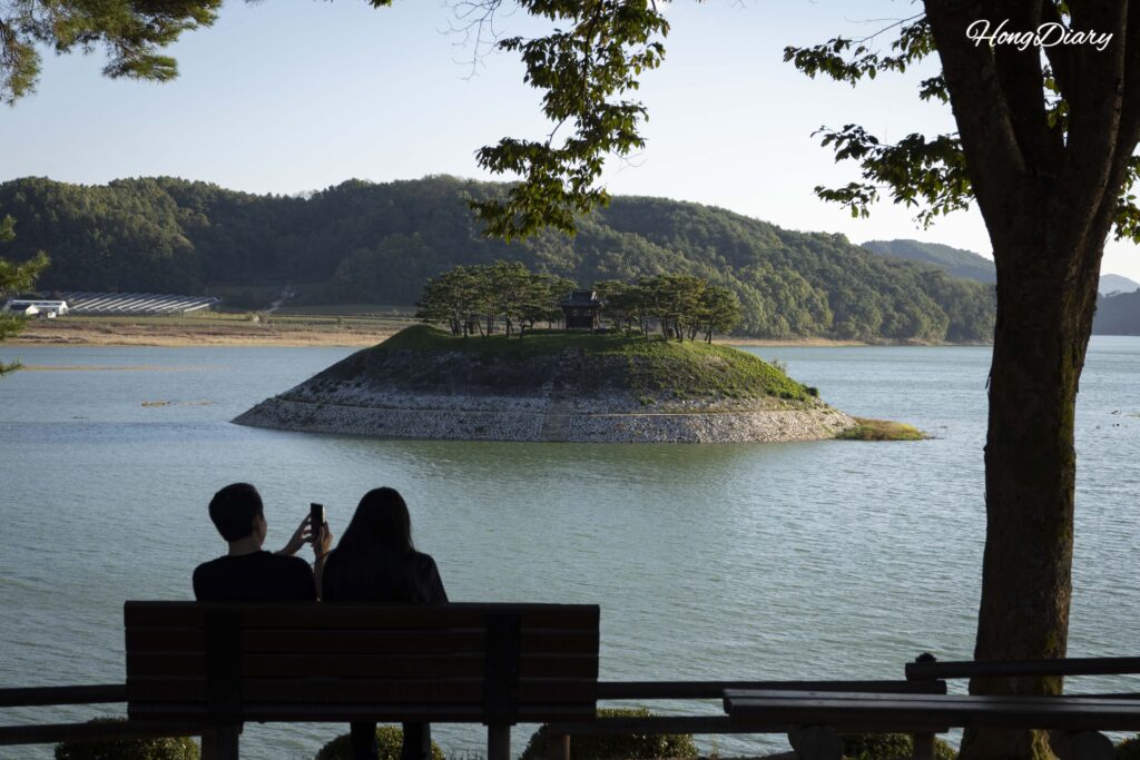 Sisadan, plataforma de piedra en una isla del río Nakdong, con una pareja sentada frente al paisaje, Andong