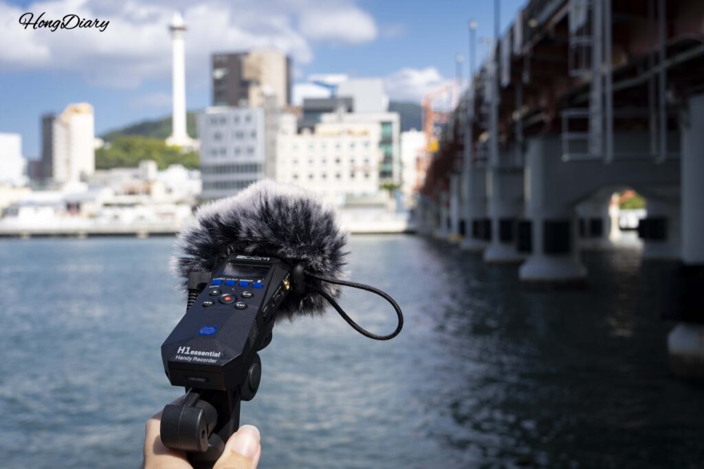 Participant using a field recorder to capture sounds under Yeongdo Bridge in Busan