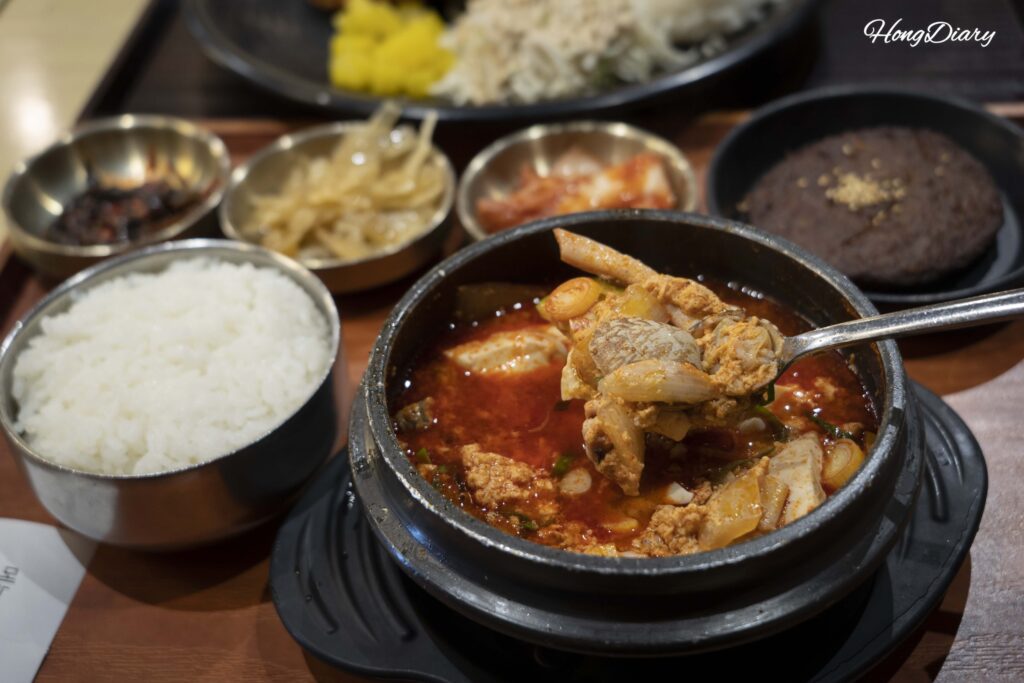 Tomando con cuchara el sundubu jjigae de mariscos en Plating, aeropuerto de Gimhae