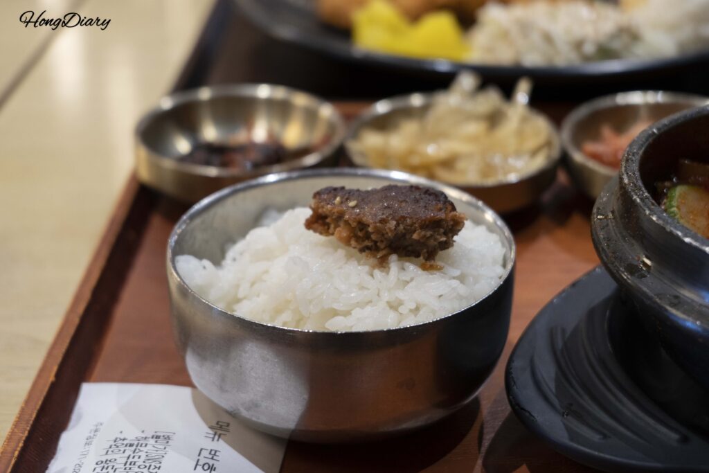 Tteokgalbi seasoned meat patty placed on top of white rice at Plating food court in Gimhae Airport