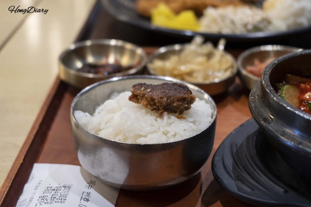 Tteokgalbi (hamburguesa coreana de carne molida) colocado sobre arroz blanco en Plating, aeropuerto de Gimhae