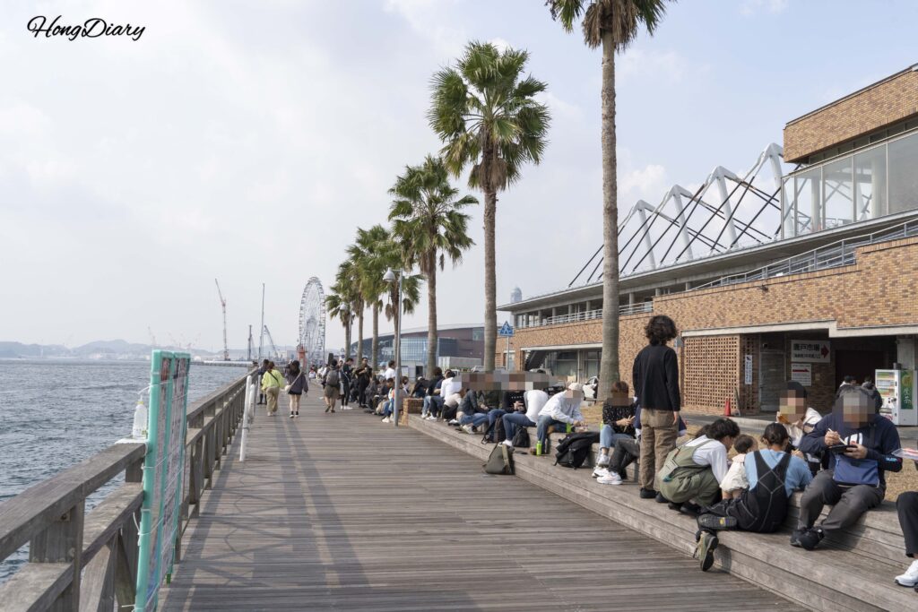 Crowds of visitors seated along the waterfront deck at Karato Market in Shimonoseki, eating sushi with a sea view
