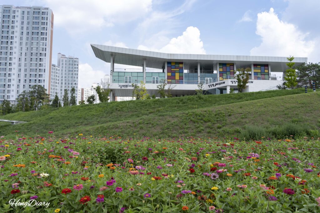梁山川沿いに咲くサルスベリ（百日紅）の花越しに見える双碧楼アートホール。梁山市、秋の風景