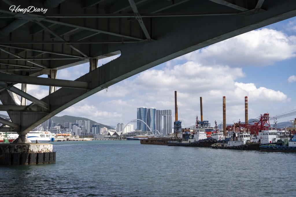 View from under Yeongdo Bridge showing fishing boats, the harbor, and Busan Station area skyline
