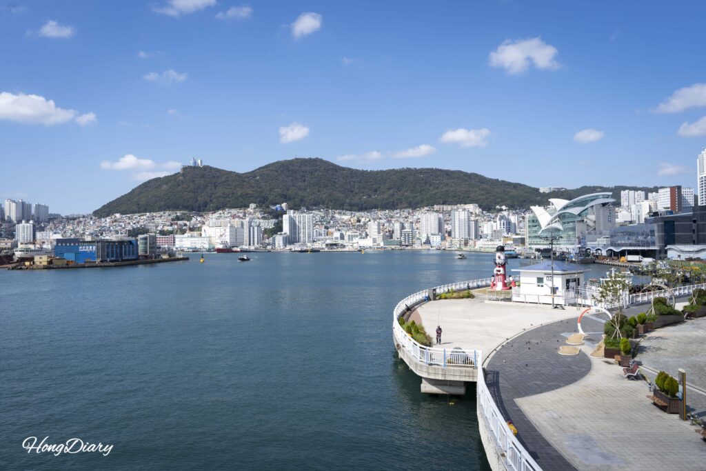 Panoramic view of Yeongdo Bridge and Yurari Square from above, with the ocean and Busan harbor in the background