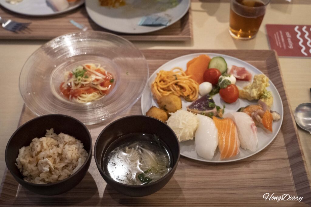 A loaded plate with fugu rice, fugu soup, cold pasta with fugu skin, sushi, katsuo tataki, and caprese salad at PUKU PUKU