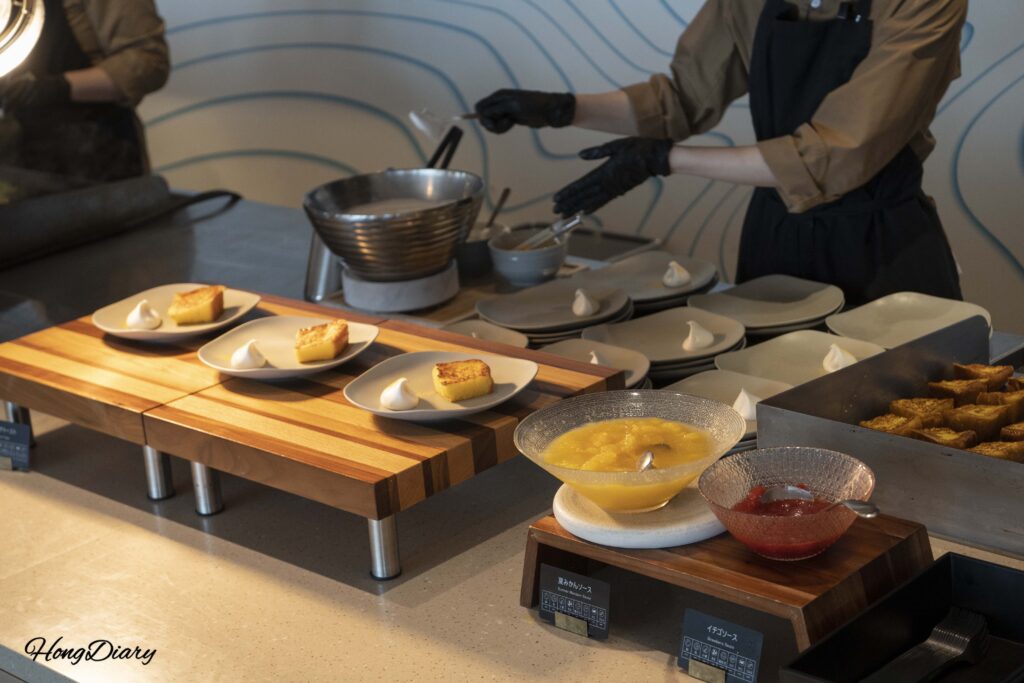 Chef adding whipped cream to freshly grilled French toast at the breakfast station in PUKU PUKU
