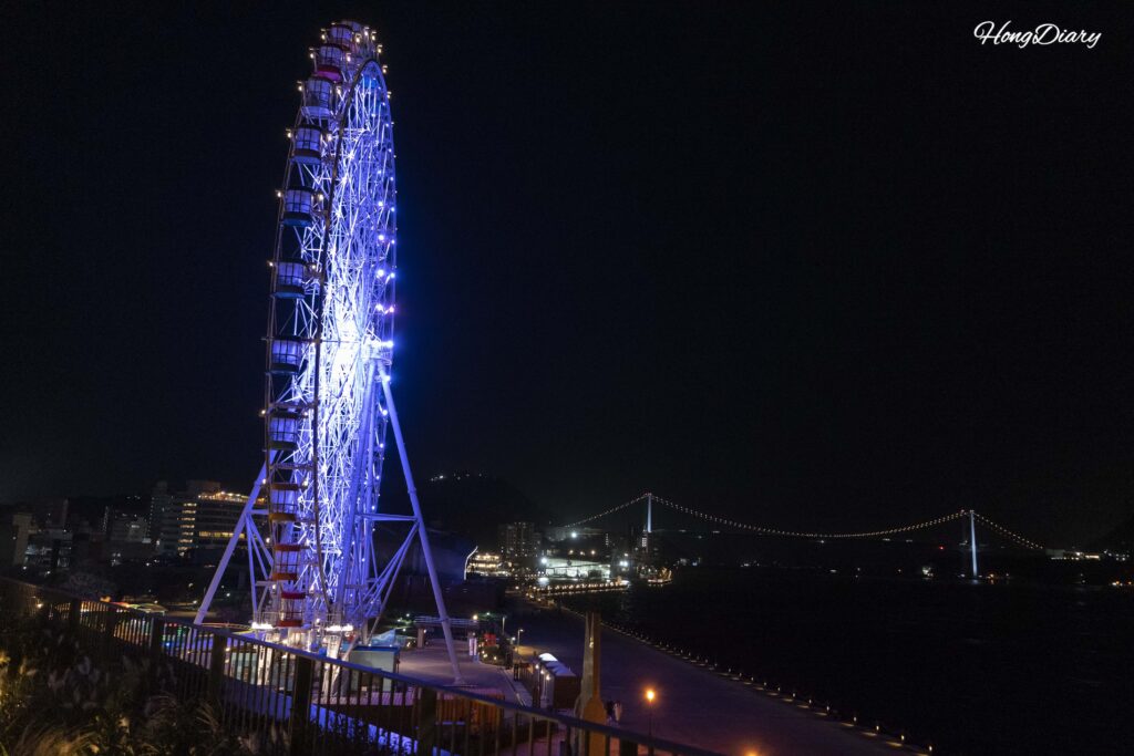 Haikara't Yokocho Ferris wheel lit up with colorful LED lights at night seen from across the Shimonoseki waterfront