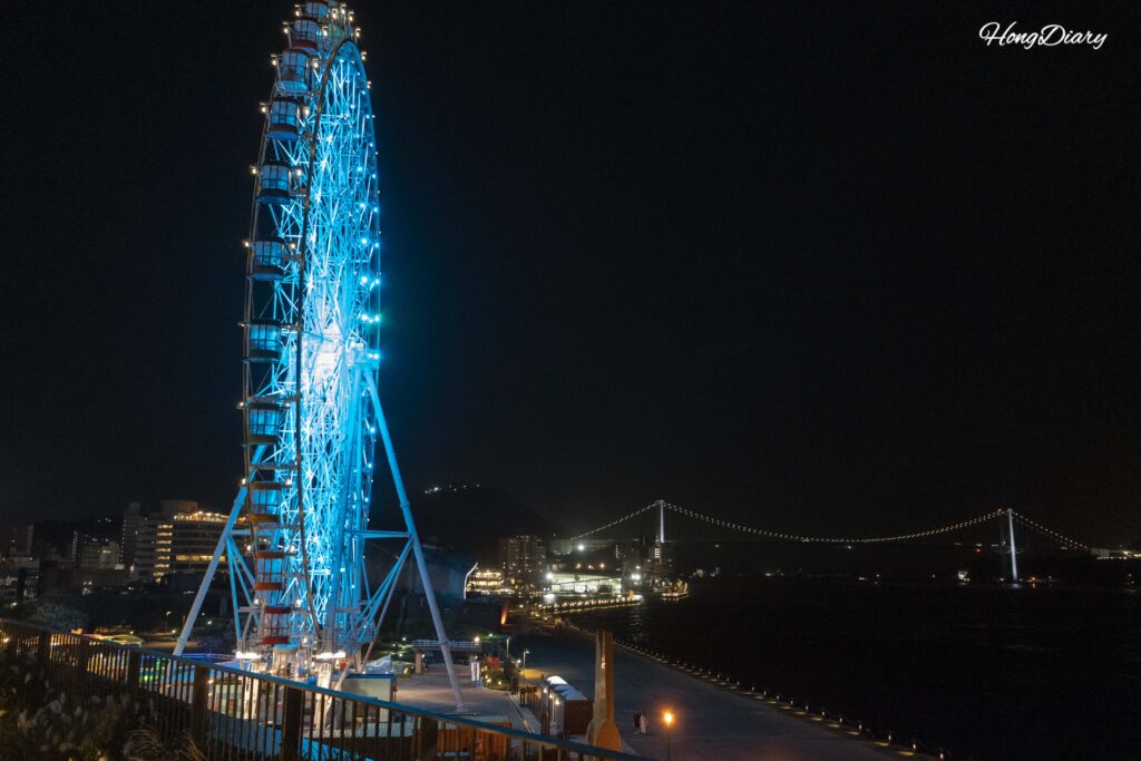 Noria de Haikara't Yokocho iluminada con luces LED de colores por la noche vista desde el alojamiento en Shimonoseki
