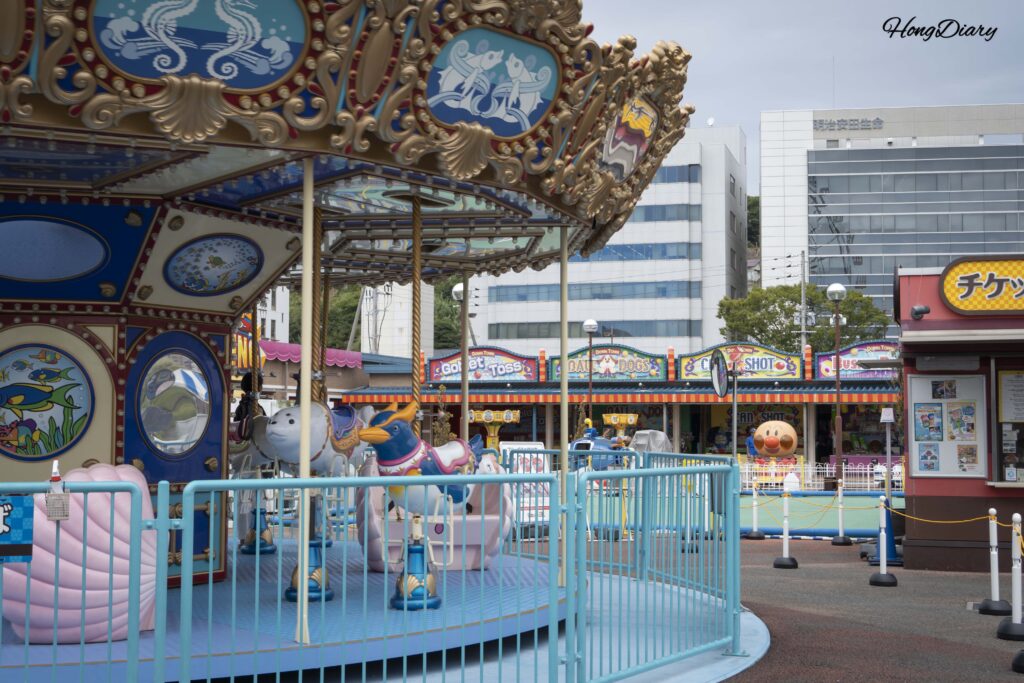 Carousel at Haikara't Yokocho featuring sea creatures instead of traditional horses with the Kanmon Strait in the background