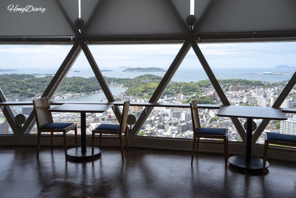 Rest lounge on the 29th floor of Kaikyo Yume Tower with wooden tables and chairs and a north-facing view of Shimonoseki city center